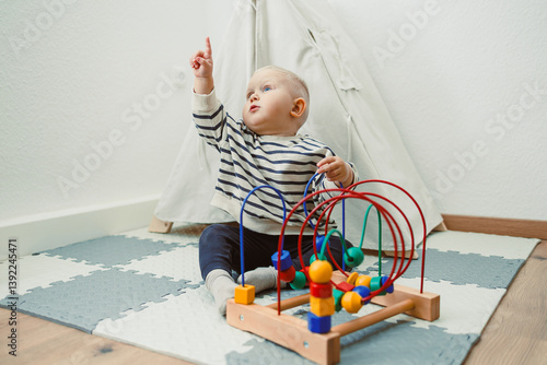 Obraz na płótnie Adorable toddler boy sitting in the living room and playing with educational toys for children. Wooden sorter for child development. Child self-employment. Development of thinking in toddlers. w salonie