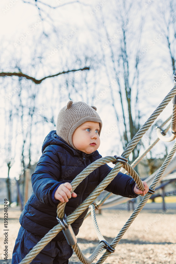 Child walking outdoors. Happy toddler boy on a walk on the playground. Child development, healthy lifestyle of the child. Boy outdoors on an autumn walk. Cheerful boy in the city park.