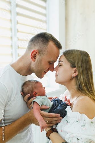 Obraz na płótnie This portrait captures a heartfelt moment of parents kissing their newborn, creating lasting memories filled with love and joy as they celebrate the profound experience of parenthood together w salonie