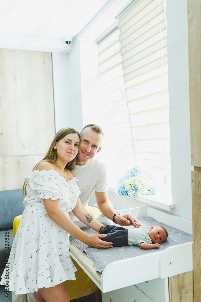 Joyful and loving parents are embracing their newborn baby in a beautifully modern and stylish nursery setting that exudes warmth and comfort, fostering a deep bond through tenderness and care