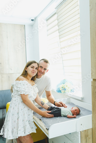Obraz na płótnie Joyful and loving parents are embracing their newborn baby in a beautifully modern and stylish nursery setting that exudes warmth and comfort, fostering a deep bond through tenderness and care w salonie