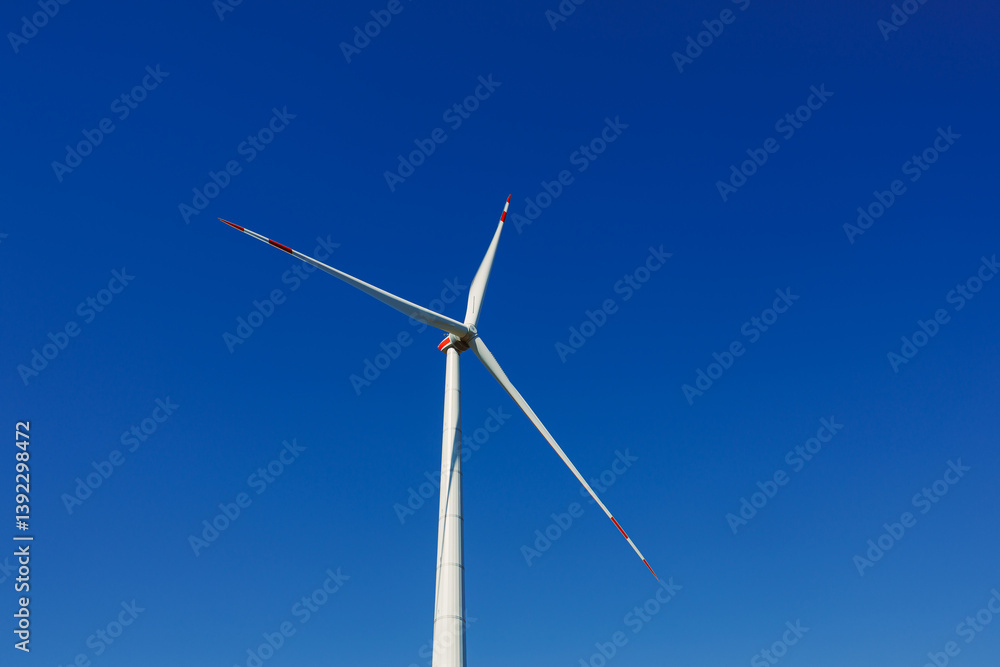Wind turbines generating energy against a clear blue sky. Wind turbines generating clean renewable energy for sustainable development Wind turbines generating energy against a clear blue sky. Wind turbines generating clean renewable energy for sustainable development