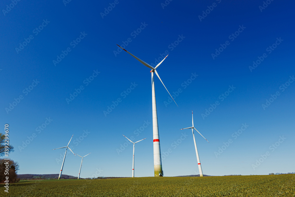 Wind turbines generating energy against a clear blue sky. Wind turbines generating clean renewable energy for sustainable development Wind turbines generating energy against a clear blue sky. Wind turbines generating clean renewable energy for sustainable development