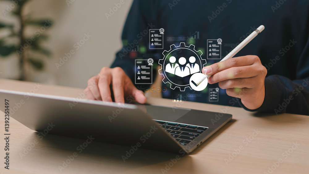Businessman using laptop and stylus with digital HR icon for employee management, recruitment analysis, and human resource optimization in modern workplace systems.