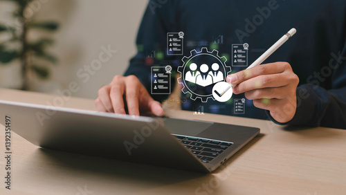 Businessman using laptop and stylus with digital HR icon for employee management, recruitment analysis, and human resource optimization in modern workplace systems.
