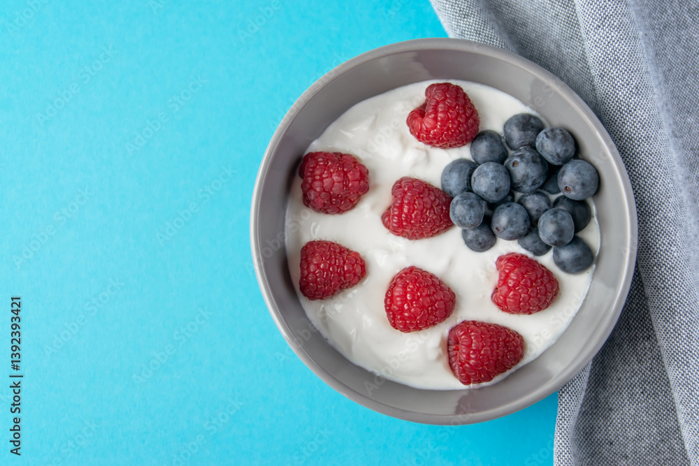 Gray bowl and natural yogurt with berries on the blue background. Gray bowl and natural yogurt with berries on the blue background.