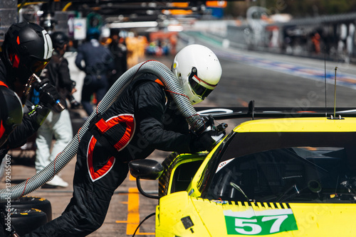 Team Mechanics Changing Tires and refuel During a High-Speed Pit Stop in the Midst of an Endurance Race	