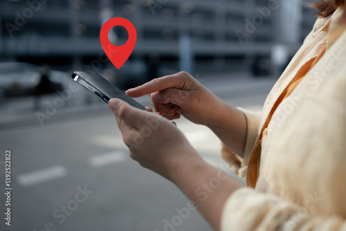 Obraz na płótnie A woman is holding her smartphone with her finger on the screen, displaying a location pin icon. This image represents digital navigation or map apps for location-based services and travel. w salonie