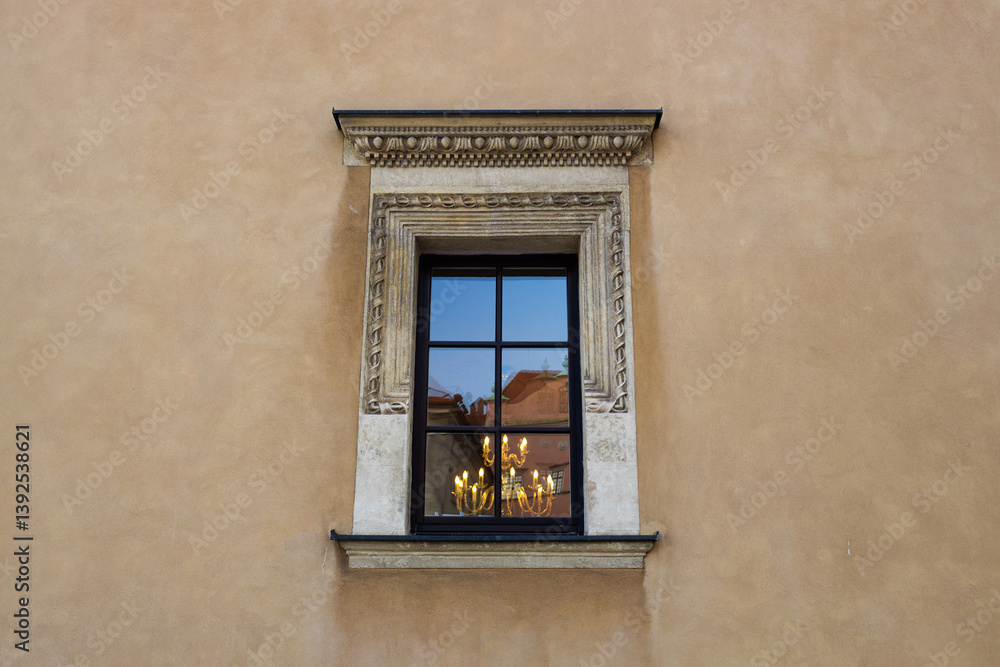 Detailed shot of an ornate window with a stone frame on an old building. The window reflects part of the surrounding architecture, adding depth to the historical atmosphere of the scene.