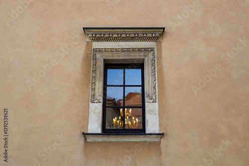 Obraz na płótnie Detailed shot of an ornate window with a stone frame on an old building. The window reflects part of the surrounding architecture, adding depth to the historical atmosphere of the scene. w salonie
