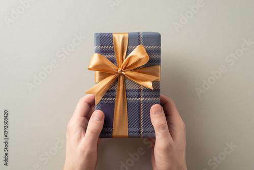 A wrapped gift with a golden bow being held, symbolizing celebration and giving photo