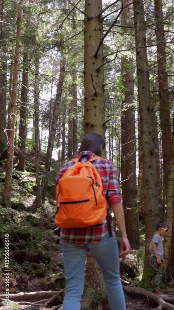 Mother and son strolling through a forest, enjoying quality family time together during a peaceful nature vacation or weekend trip. Vertical video. Mother and son strolling through a forest, enjoying quality family time together during a peaceful nature vacation or weekend trip. Vertical video.