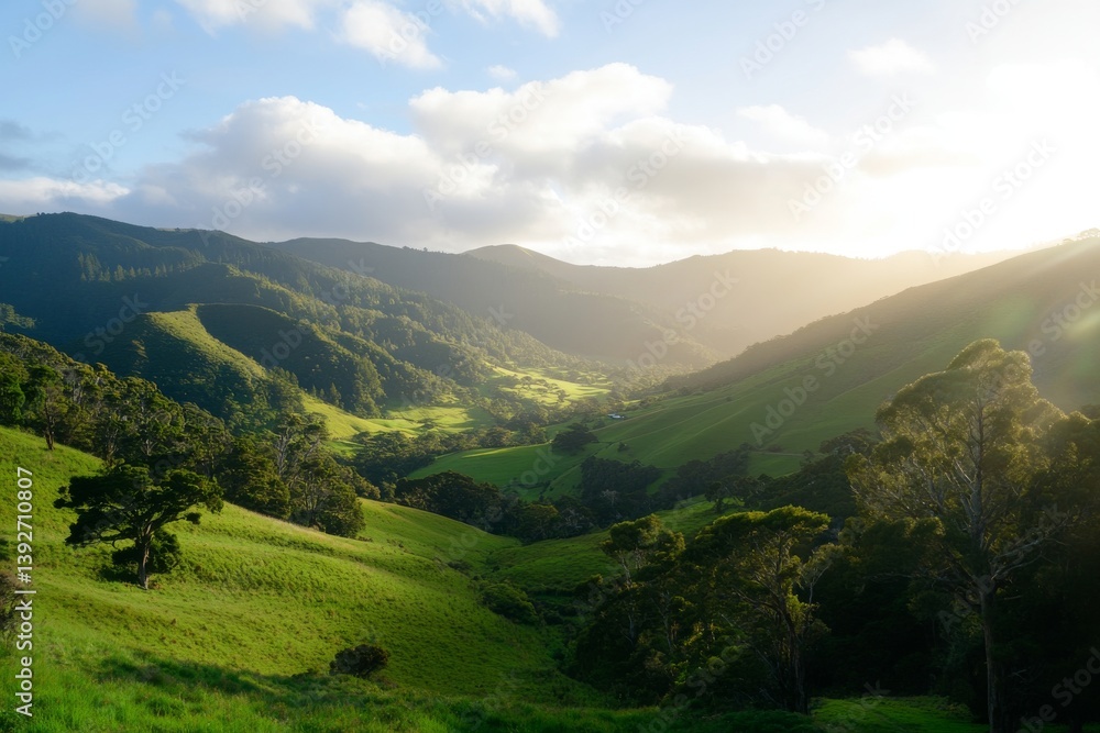 Fototapeta premium Lush valley with sunlight beaming between mountains. Hilly terrain