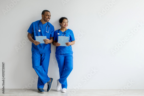 Billede på lærred African American man and woman in medical scrubs looking aside at copy space, me