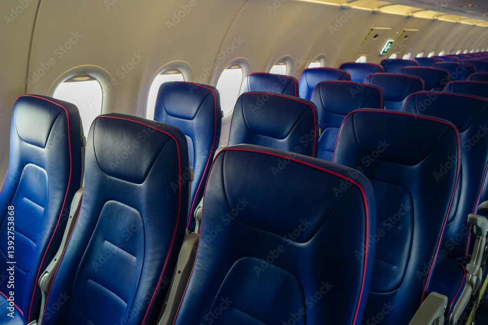 Fototapeta premium Rows of empty blue leather seats with three seats in the cabin of a cheap airline