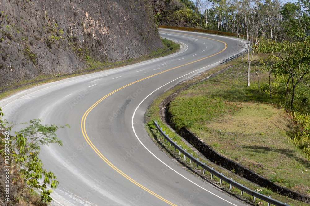 Winding road curves through lush greenery in a mountainous area under bright daylight. Dominican Republic. Winding road curves through lush greenery in a mountainous area under bright daylight. Dominican Republic.