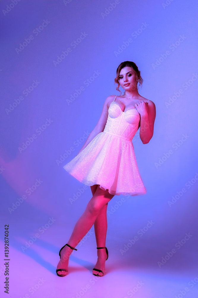 Model in a sparkling white dress poses against a colorful backdrop during a photoshoot in a studio setting Model in a sparkling white dress poses against a colorful backdrop during a photoshoot in a studio setting