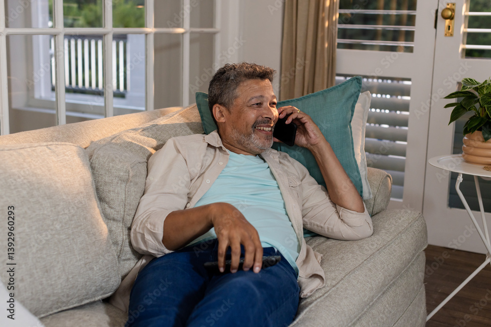 Senior man relaxing on couch, talking on smartphone at home, smiling happily Senior man relaxing on couch, talking on smartphone at home, smiling happily