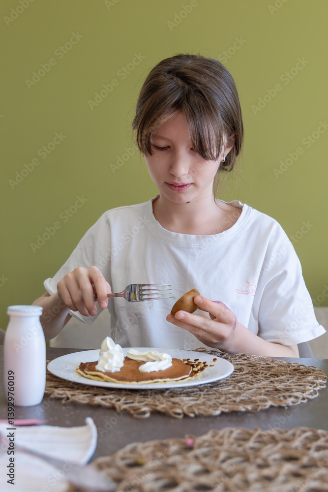 Girl Eating Pancakes with Whipped Cream. Young girl enjoying breakfast with pancakes and whipped cream, holding kiwi fruit and fork, seated at a cozy table setting. Girl Eating Pancakes with Whipped Cream. Young girl enjoying breakfast with pancakes and whipped cream, holding kiwi fruit and fork, seated at a cozy table setting.