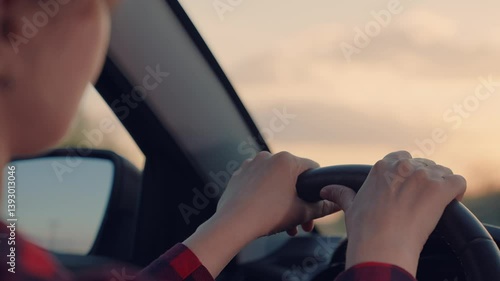 Wallpaper Mural Woman is driving a car with her hand on the steering wheel. The sun is setting, casting a warm glow on the scene Torontodigital.ca