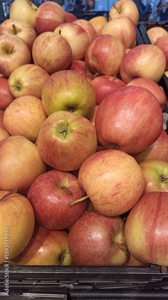 Fresh red and yellow apples piled in a display crate at a grocery store. The image reflects themes of healthy lifestyle, freshness and natural nutrition Fresh red and yellow apples piled in a display crate at a grocery store. The image reflects themes of healthy lifestyle, freshness and natural nutrition