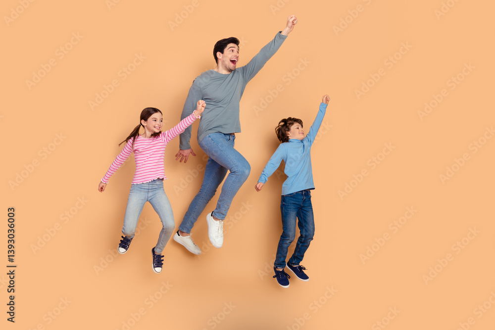 Obraz premium Family bonding concept with father and two children jumping happily against a beige background