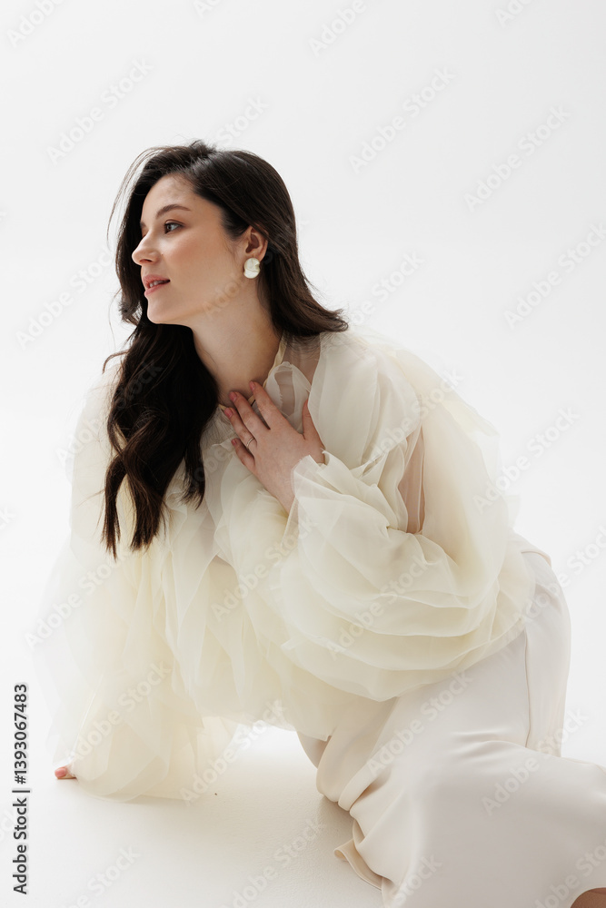 Pregnant woman in a white flowing dress leaning against a white wall. Pregnant woman in a white flowing dress leaning against a white wall.