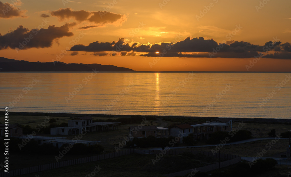 Fototapeta premium Golden sunset over tranquil waters and distant hills, casting reflections along the shoreline as day transitions to night