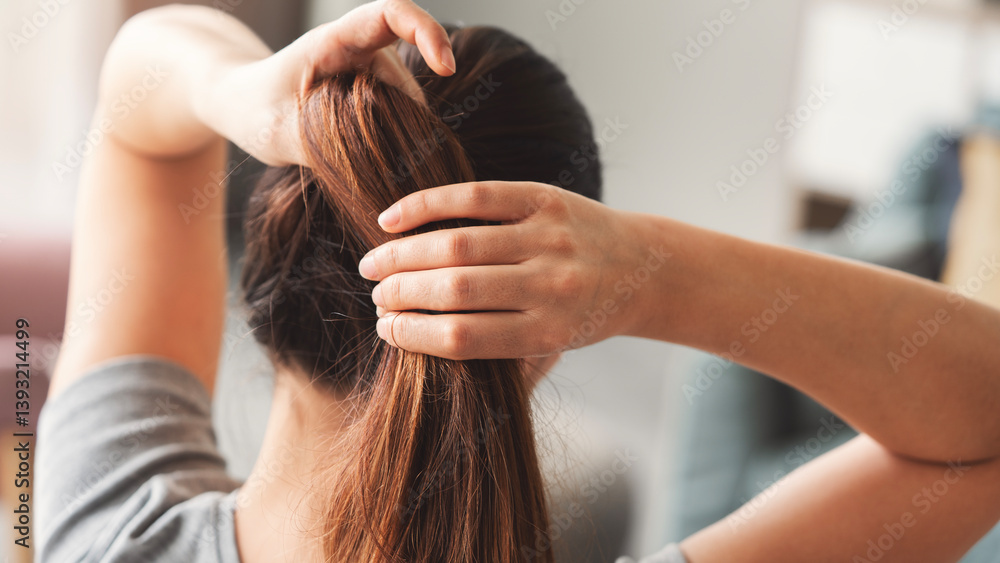 Naklejka premium Young woman tying her long hair