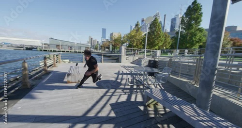 Young parkour athlete jumping off rails and rolling on outdoor table before running off