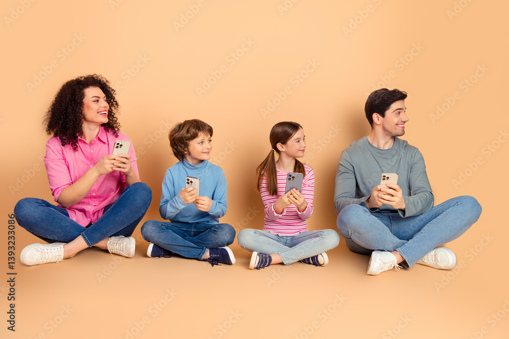 Cheerful family sitting on a beige background, holding smartphones and sharing laughter, symbolizing bonding