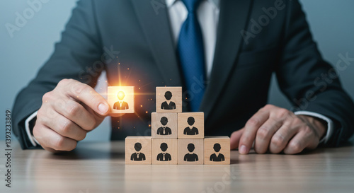 Wallpaper Mural A confident businessman strategically placing a key employee atop a growing team, signifying career advancement and team success with warm light illuminating the chosen individual. Torontodigital.ca