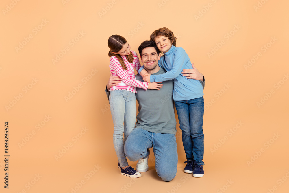 Loving Family Portrait Featuring a Smiling Father With His Daughter and Son Hugging Against a Beige Background Loving Family Portrait Featuring a Smiling Father With His Daughter and Son Hugging Against a Beige Background