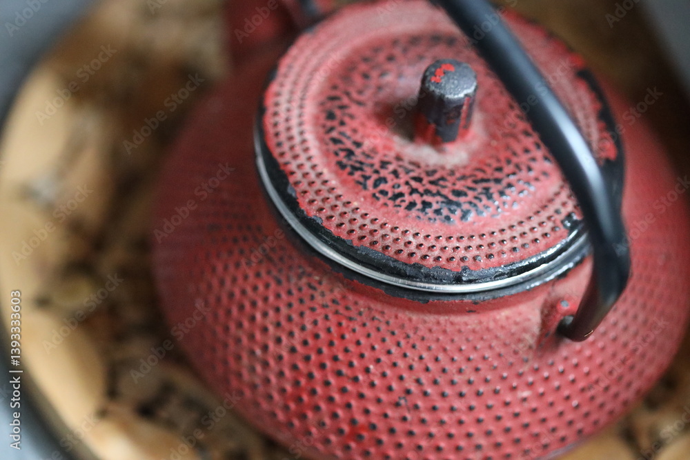 A bright red teapot sits atop a natural wood plate, perfect for serving tea or as a decorative piece