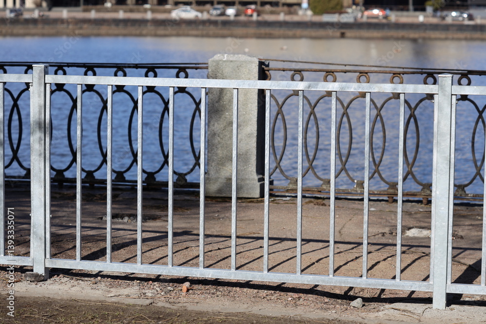 A metal fence running along the edge of a body of water, suitable for use in scenes where a boundary or separation is needed.