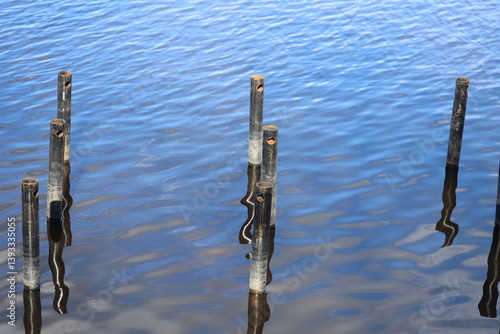 Obraz na płótnie A row of poles sticking out of the water, possibly used for fishing or swimming. w salonie