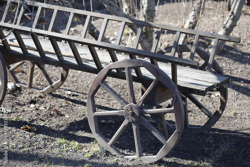 A simple wooden bench sits beside a traditional wooden wagon, perfect for rustic outdoor scenes or vintage-themed settings.