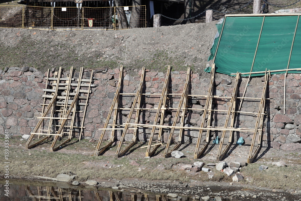 A group of wooden ladders leaned against a stone wall, great for backdrops or decorative scenes.