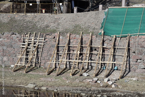 Obraz na płótnie A group of wooden ladders leaned against a stone wall, great for backdrops or decorative scenes. w salonie