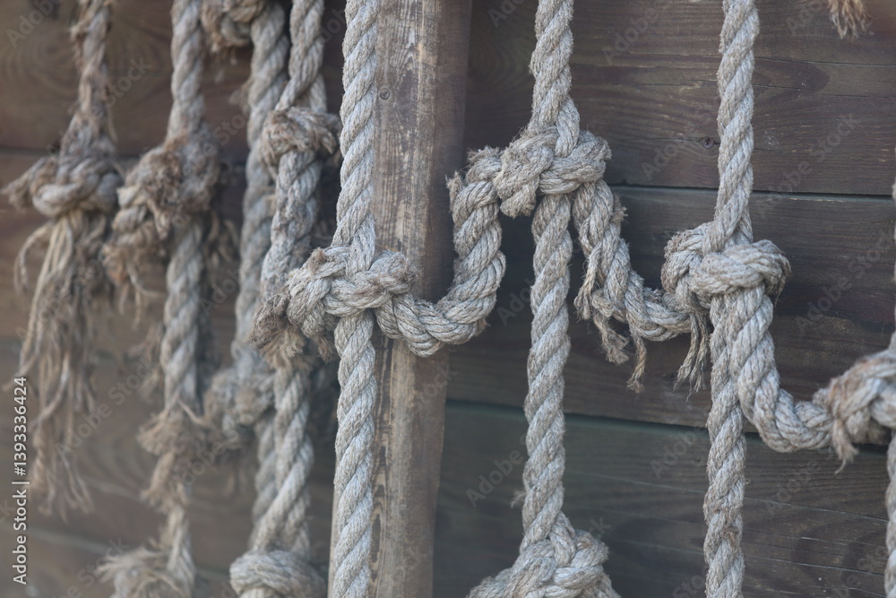 A bunch of rope hanging on the side of a building, potential for climbing or support.