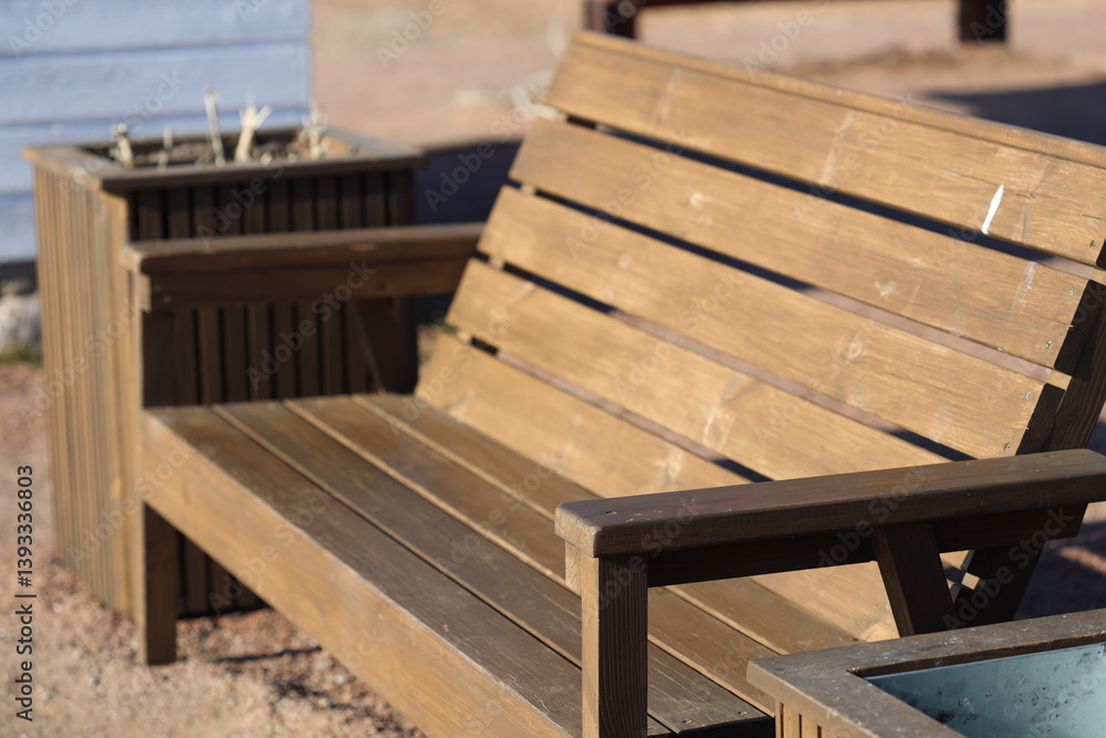 A simple wooden bench sits beside a colorful planter filled with greenery.