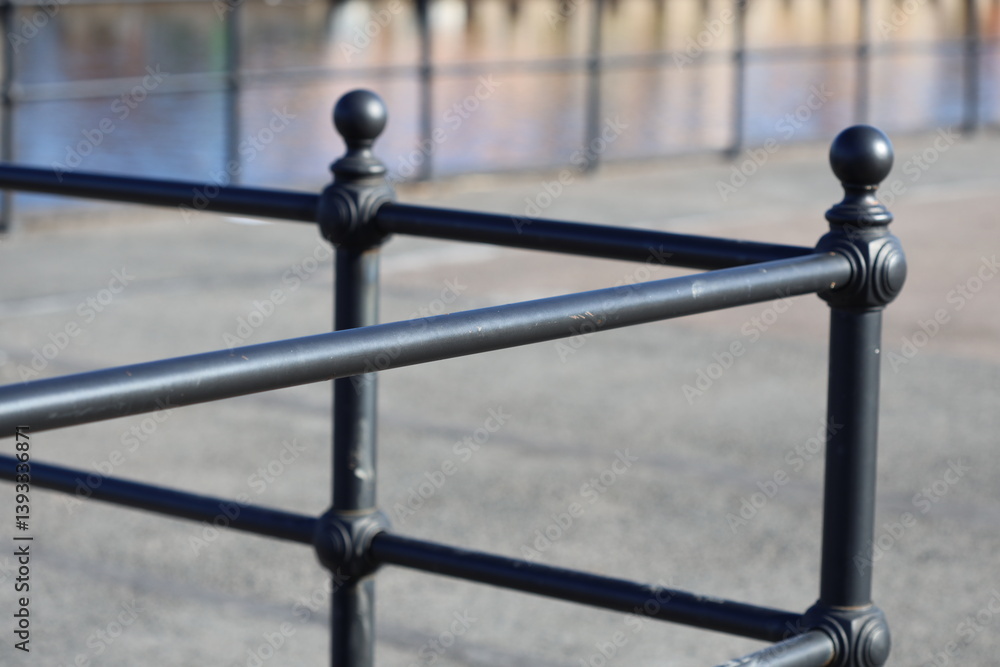 A close-up shot of a metal fence with a body of water in the background, perfect for use as a decorative element or to add a touch of tranquility to your design.