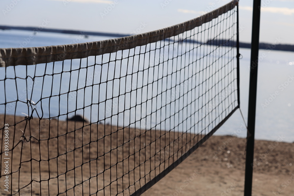 A volleyball net on the beach near the water, perfect for a game or a relaxing day at the shore.