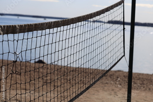 A volleyball net on the beach near the water, perfect for a game or a relaxing day at the shore.