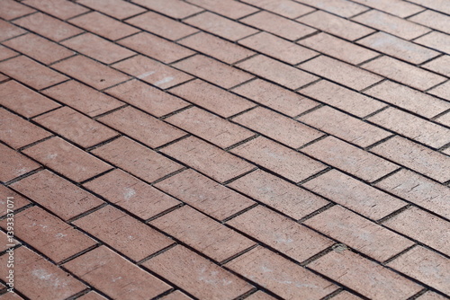 Obraz na płótnie Close-up shot of a worn red brick sidewalk with subtle texture and imperfections. w salonie