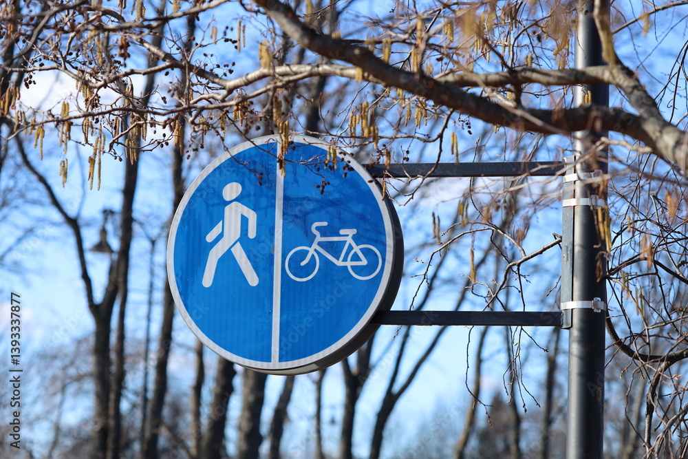 A person rides a bike in front of a blue street sign, providing a clear directional guide.