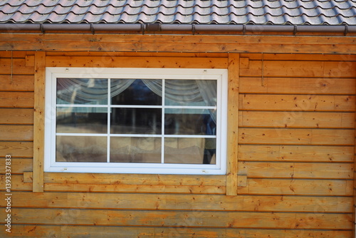 Obraz na płótnie A domestic cat is sitting in the window of a traditional wooden house. w salonie