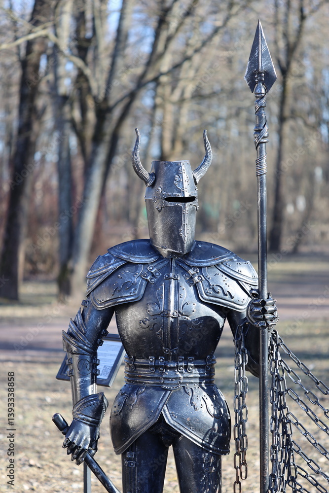 A bronze statue of a knight on top of a chain link fence, ornate details and texture.