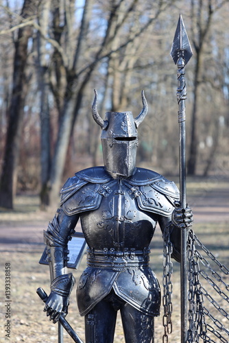 Obraz na płótnie A bronze statue of a knight on top of a chain link fence, ornate details and texture. w salonie