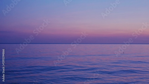 A sailboat glides across the calm waters at sunset